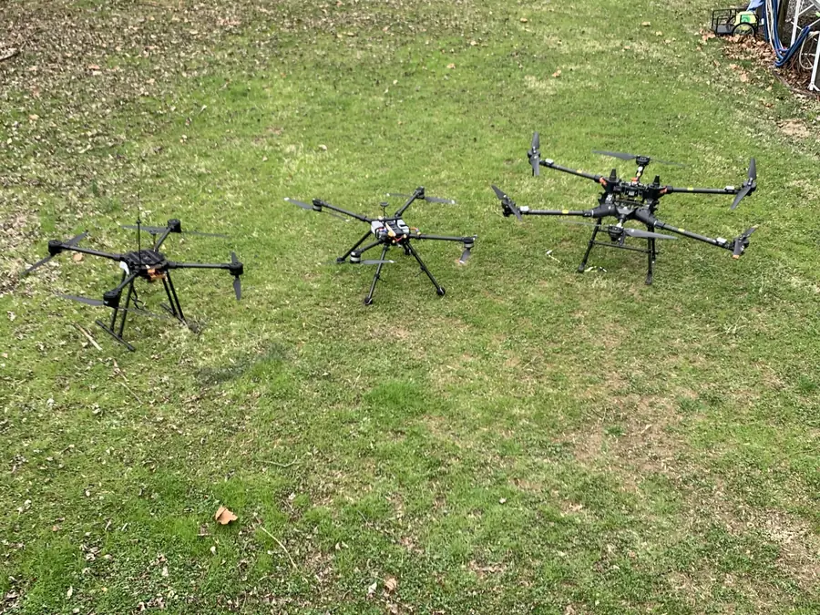 Three multirotor drones on a grass field